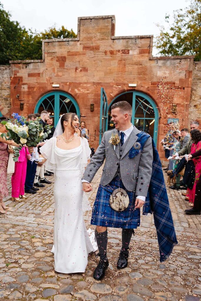 Detailed view of a wedding dress being adjusted by a professional tailor.