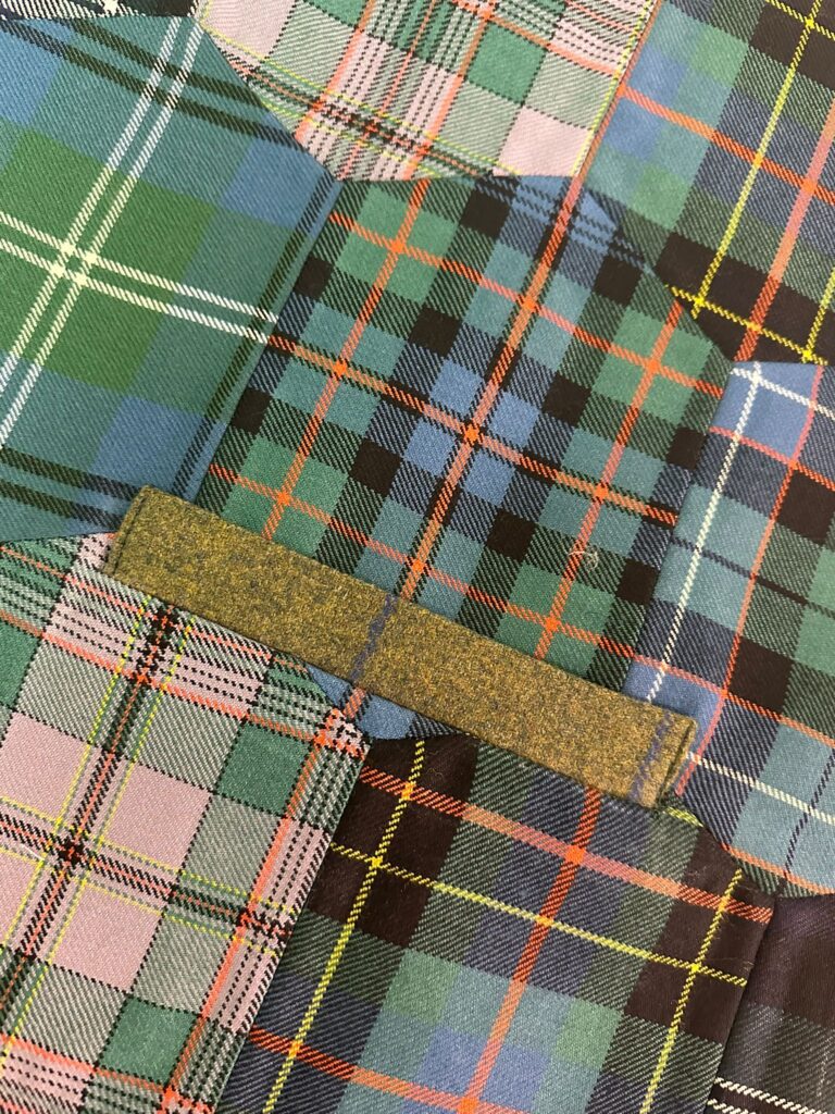 Close-up of high-quality tartan fabric being prepared for kilt alterations in Dunfermline.