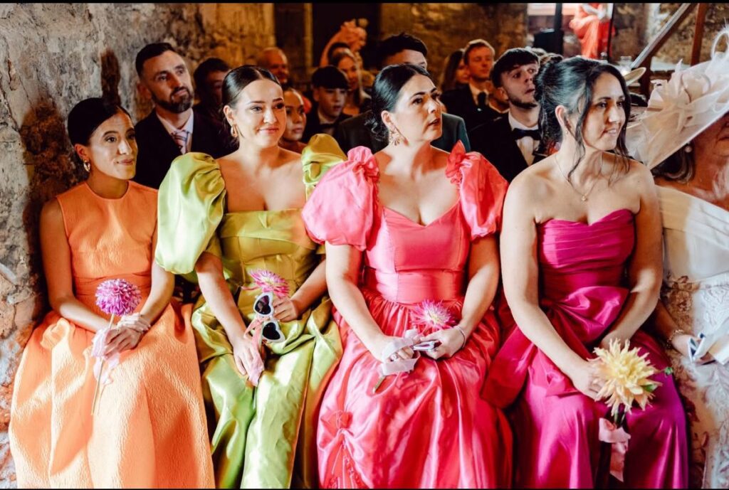 Detailed view of colourful bridesmaid gowns focusing on the puff sleeves and necklines.